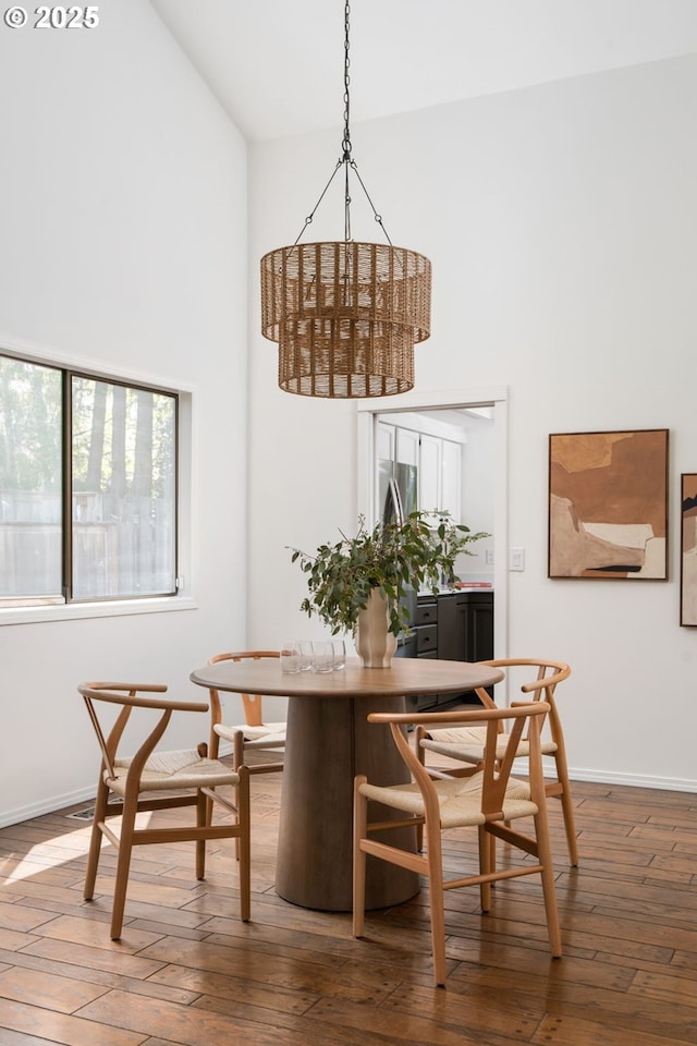 dining space featuring high vaulted ceiling, baseboards, and hardwood / wood-style floors