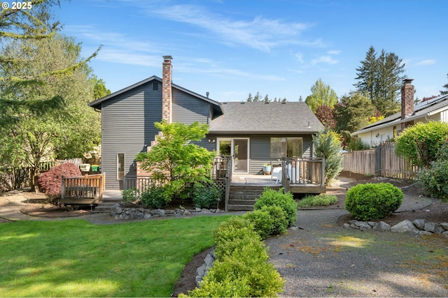 view of front of home featuring roof with shingles, fence, a front yard, and a deck