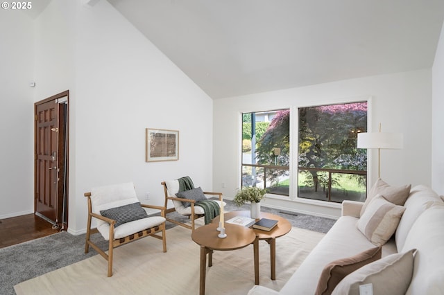 carpeted living room with baseboards, visible vents, and high vaulted ceiling