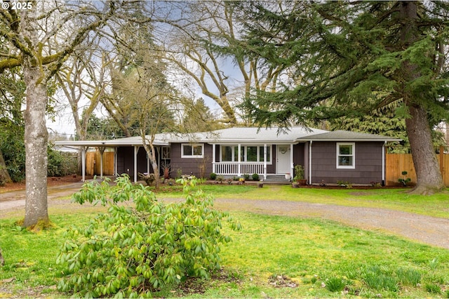 ranch-style house featuring a front yard, fence, covered porch, and dirt driveway