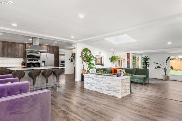 living area with dark wood finished floors, a skylight, and recessed lighting