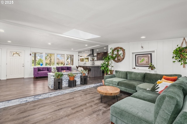 living area with recessed lighting, a skylight, and wood finished floors