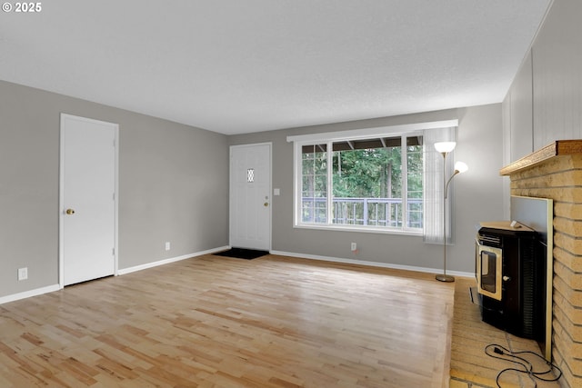 29652 Lusk Rd, Eugene, OR 97405 - unfurnished living room featuring a wood stove, light wood-style flooring, and baseboards