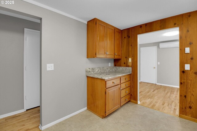 29652 Lusk Rd, Eugene, OR 97405 - kitchen featuring a wall unit AC, baseboards, light wood-type flooring, brown cabinets, and ornamental molding