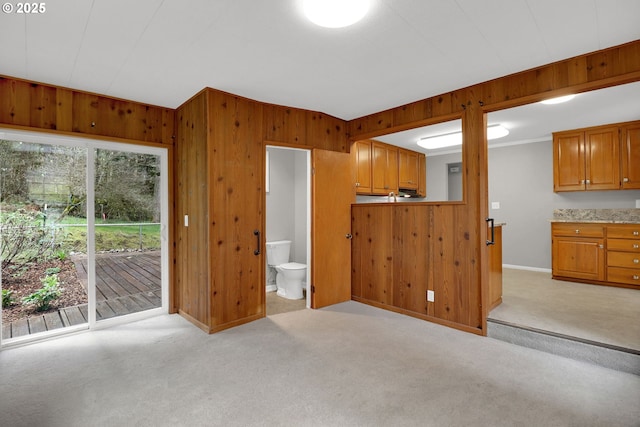 29652 Lusk Rd, Eugene, OR 97405 - kitchen featuring wooden walls, light colored carpet, baseboards, brown cabinets, and crown molding