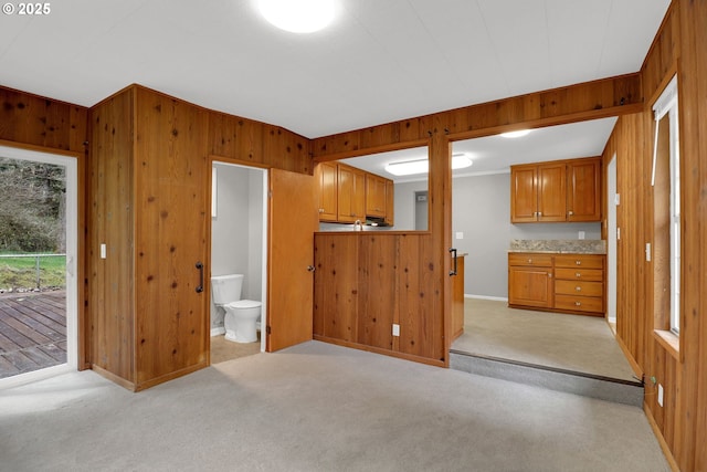 29652 Lusk Rd, Eugene, OR 97405 - kitchen featuring wood walls, brown cabinets, light carpet, baseboards, and crown molding