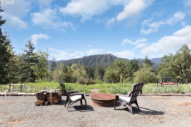 exterior space with a mountain view, an outdoor fire pit, and a forest view