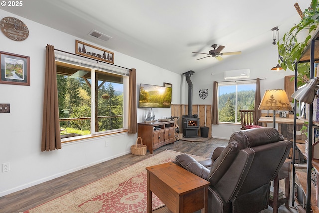 living room featuring visible vents, a wood stove, dark wood-type flooring, a wall mounted AC, and a ceiling fan