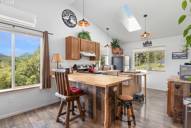 kitchen with a breakfast bar, stainless steel appliances, a skylight, a wall mounted AC, and butcher block counters