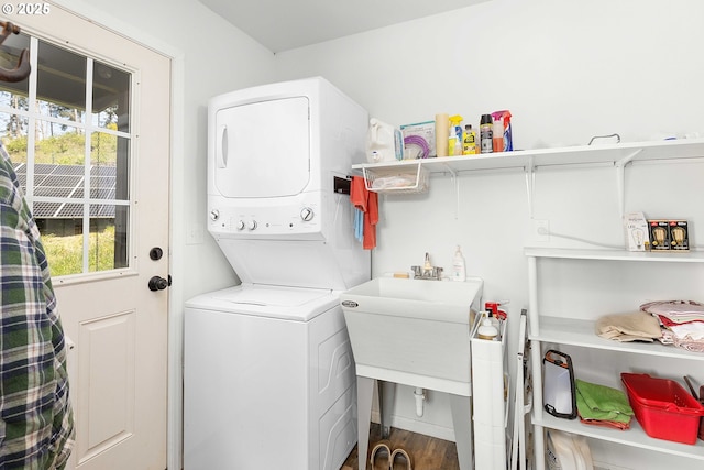 laundry area featuring laundry area, stacked washing maching and dryer, and wood finished floors