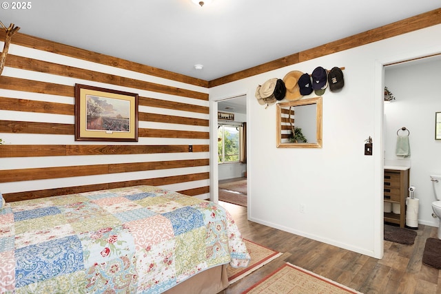 bedroom featuring baseboards, wood walls, and wood finished floors