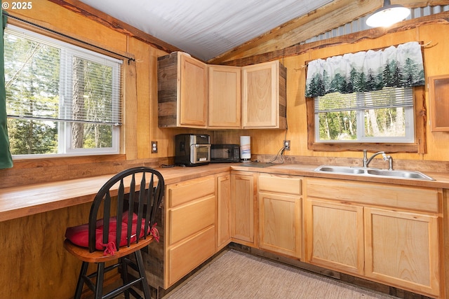 kitchen featuring butcher block counters, light brown cabinets, wooden walls, a sink, and vaulted ceiling