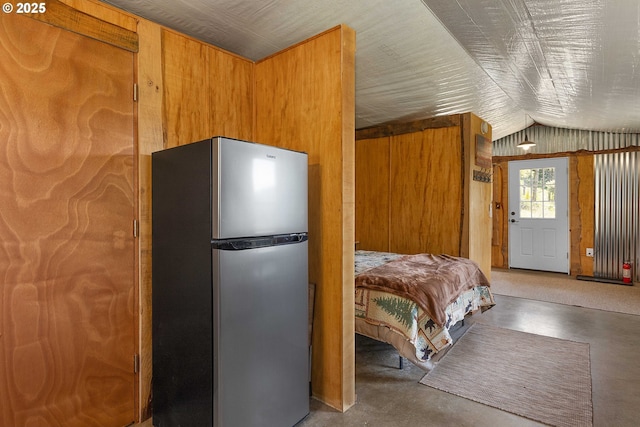 bedroom featuring freestanding refrigerator, lofted ceiling, and finished concrete flooring