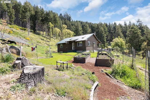 view of yard with fence, a vegetable garden, and a wooded view