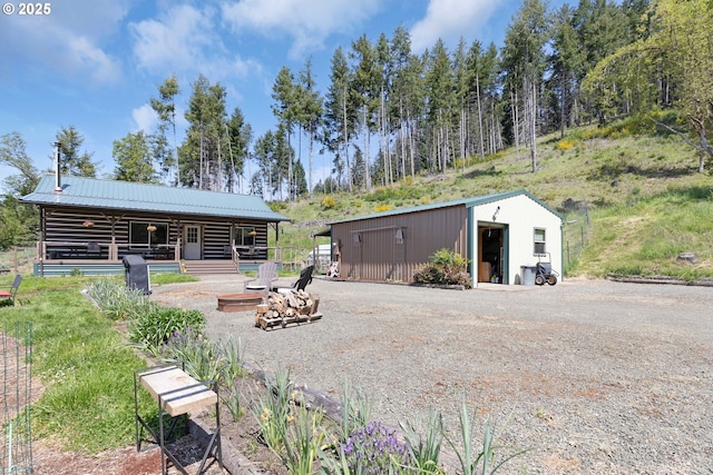 back of house featuring metal roof, an exterior structure, an outbuilding, and log siding