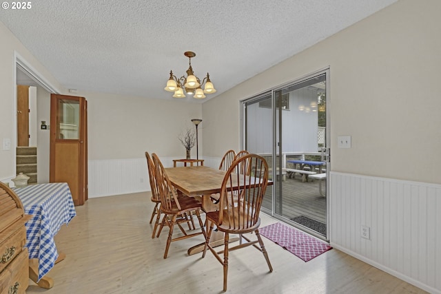 85304 Nestle Way, Pleasant Hill, OR 97455 - dining room with light wood finished floors, a chandelier, wainscoting, a textured ceiling, and stairway