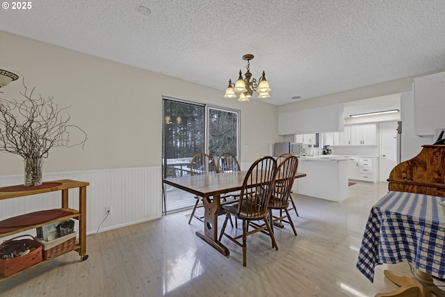 85304 Nestle Way, Pleasant Hill, OR 97455 - dining space featuring a chandelier, a wainscoted wall, light wood-style flooring, and a textured ceiling