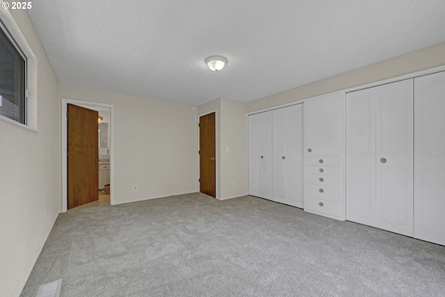 85304 Nestle Way, Pleasant Hill, OR 97455 - unfurnished bedroom with multiple closets, a textured ceiling, carpet flooring, and ensuite bathroom