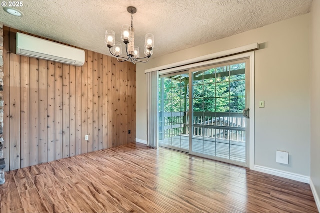 16127 NE Caples Rd, Brush Prairie, WA 98606 - unfurnished room with a wall unit AC, a chandelier, wood finished floors, a textured ceiling, and wood walls