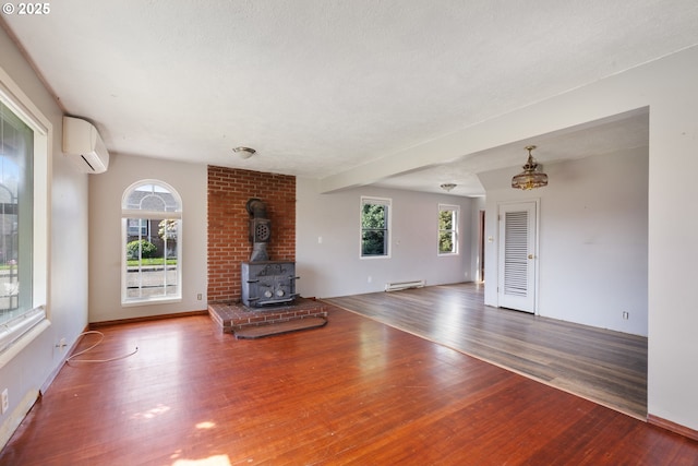 520 Elm Ave, Tillamook, OR 97141 - unfurnished living room featuring a wall unit AC, a baseboard heating unit, wood finished floors, and a wood stove