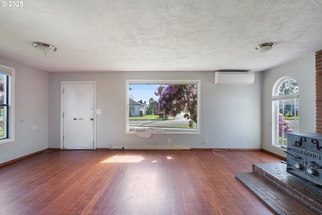 520 Elm Ave, Tillamook, OR 97141 - unfurnished living room with an AC wall unit, wood finished floors, a textured ceiling, plenty of natural light, and baseboards