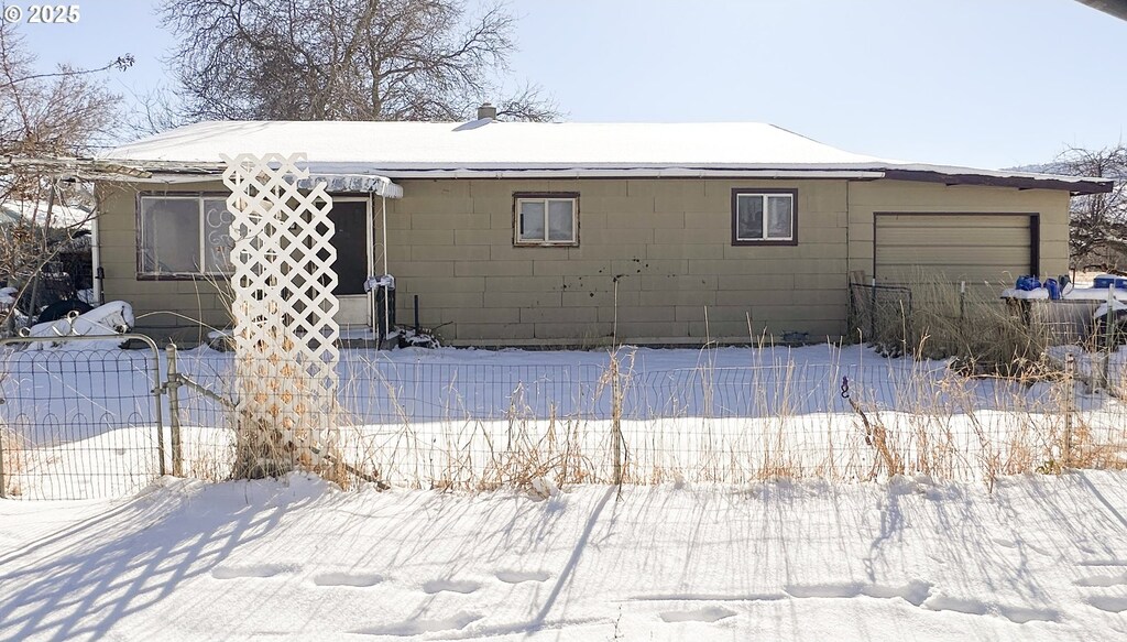 snow covered back of property featuring a garage