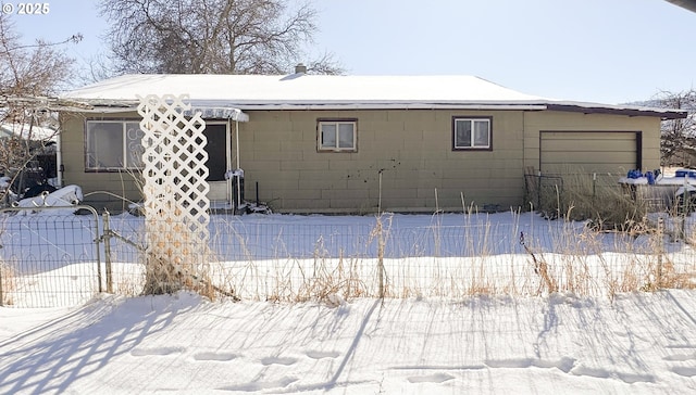 snow covered back of property featuring a garage