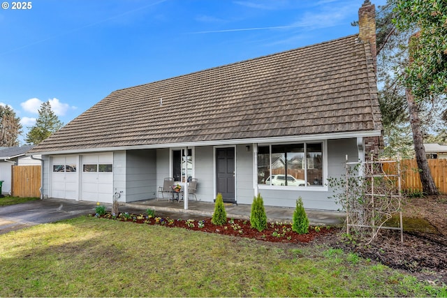 view of front of home with fence, covered porch, driveway, and a chimney