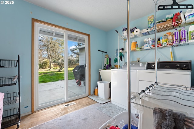 laundry room with visible vents, washer and clothes dryer, a sink, wood finished floors, and laundry area