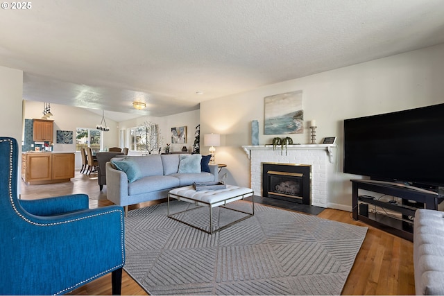 living area featuring a fireplace, vaulted ceiling, wood finished floors, and a textured ceiling