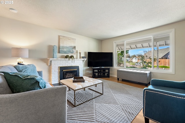 living area featuring a textured ceiling, a brick fireplace, and wood finished floors