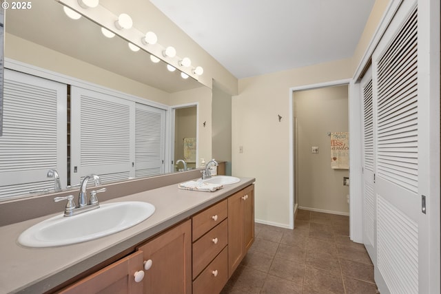 full bath with a closet, double vanity, baseboards, and tile patterned floors