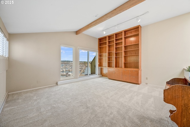 unfurnished living room with light colored carpet, baseboards, and rail lighting