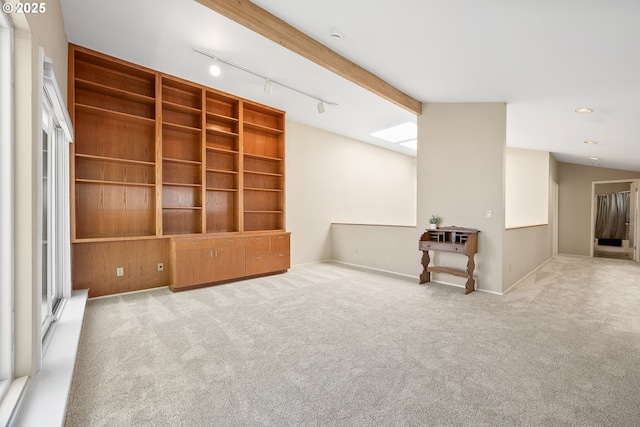 carpeted spare room featuring rail lighting, beamed ceiling, and baseboards
