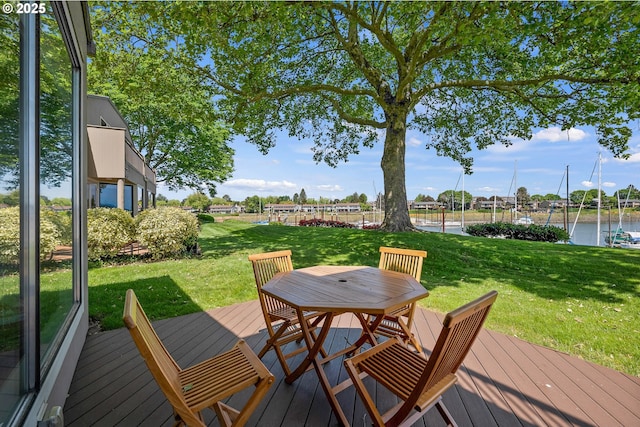 deck with a lawn, a water view, and outdoor dining space