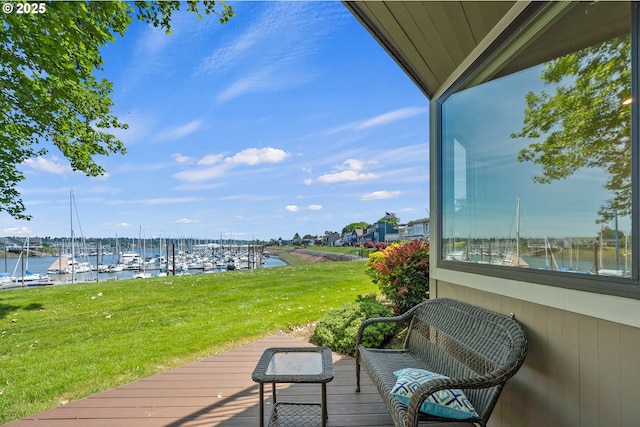 wooden terrace featuring a water view, view of marina, and a yard