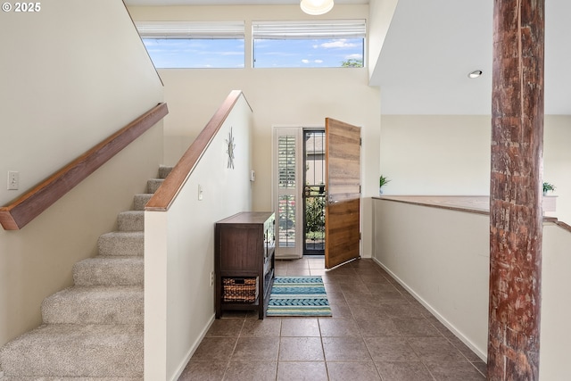 tiled foyer entrance featuring baseboards and stairs
