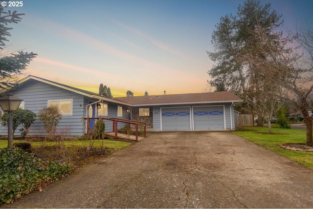 ranch-style house featuring a yard, driveway, and an attached garage