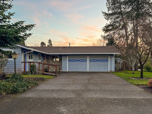 ranch-style home with driveway, a chimney, an attached garage, and a lawn