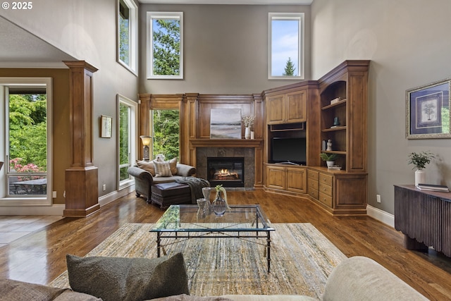 24800 SW Big Fir Rd, West Linn, OR 97068 - living room with a high ceiling, ornate columns, a fireplace, baseboards, and dark wood finished floors