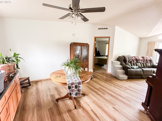 dining area with ceiling fan, light wood finished floors, baseboards, and vaulted ceiling