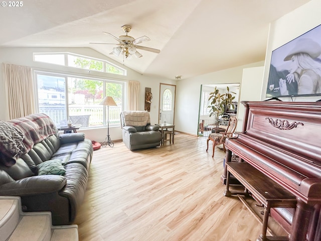 living area featuring vaulted ceiling, light wood finished floors, a ceiling fan, and baseboards