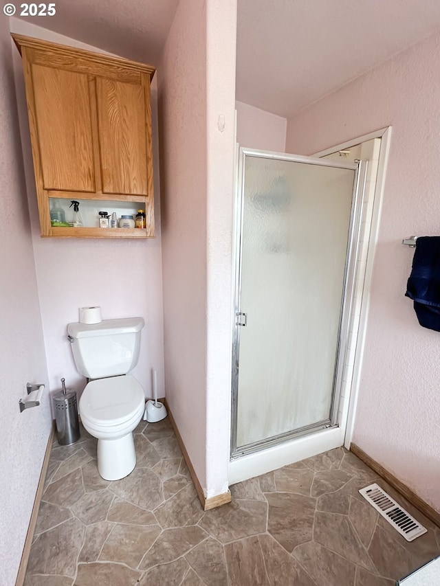 full bathroom featuring baseboards, a stall shower, and toilet