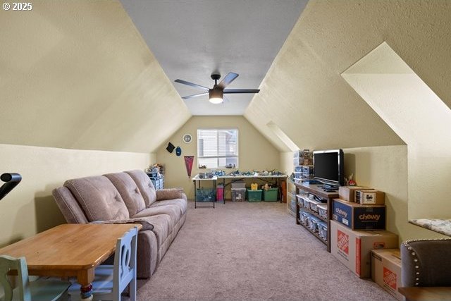 interior space with vaulted ceiling, light carpet, and ceiling fan