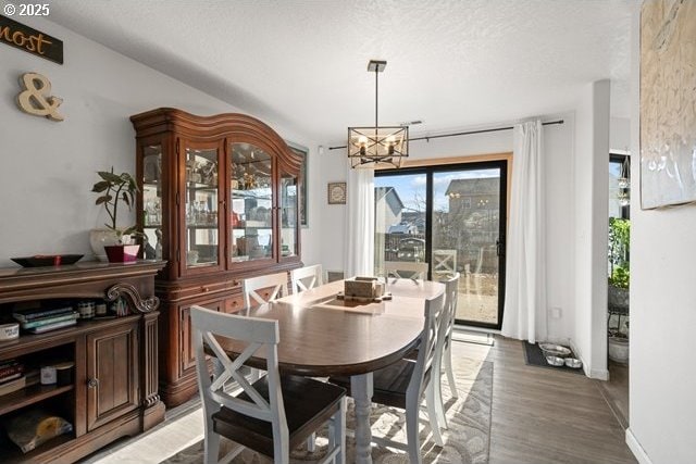 dining room with hardwood / wood-style floors, a textured ceiling, and a notable chandelier