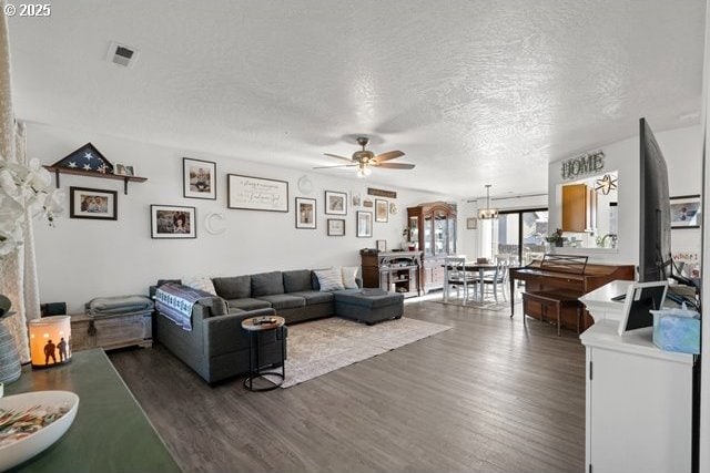 living room featuring dark wood-type flooring, ceiling fan, and a textured ceiling