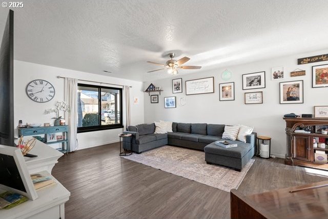 living room with ceiling fan, dark hardwood / wood-style flooring, and a textured ceiling