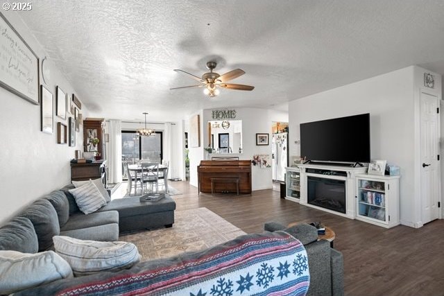 living room with dark hardwood / wood-style flooring, ceiling fan with notable chandelier, and a textured ceiling