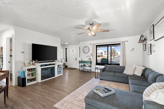 living room with ceiling fan, dark hardwood / wood-style floors, and a textured ceiling