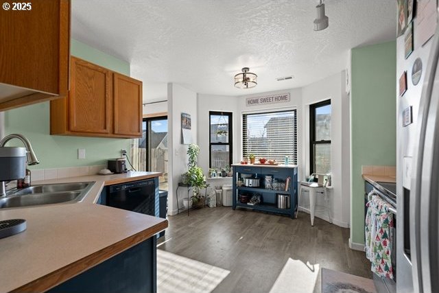 kitchen with dishwasher, sink, dark hardwood / wood-style flooring, stainless steel fridge with ice dispenser, and a textured ceiling